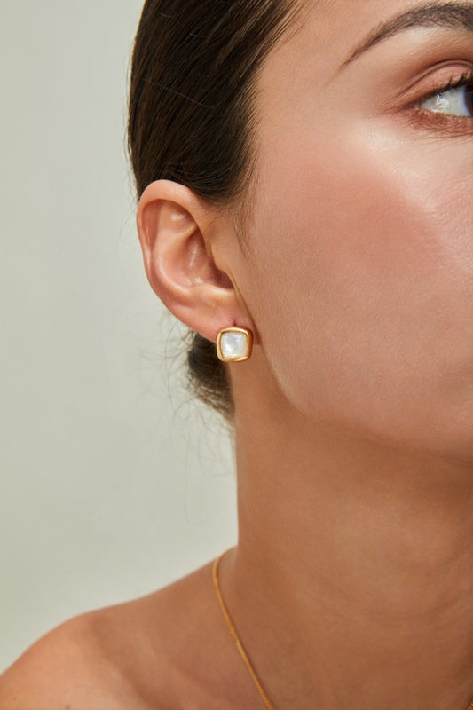 Close-up of a person wearing a Siren Mode 18K Gold Plated 925 Silver Square Baroque Pearl Stud Earring. The person has their hair pulled back, revealing a smooth complexion and minimal makeup. The neutral background highlights the earring as the main subject.