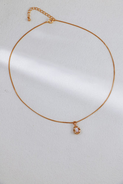 A sophisticated Elegant Gold-Plated Sterling Silver Necklace with a thin chain and adjustable length by Siren Mode, featuring a small teardrop-shaped pendant adorned with a pearl-like center. This exquisite piece is showcased on a light, neutral background.