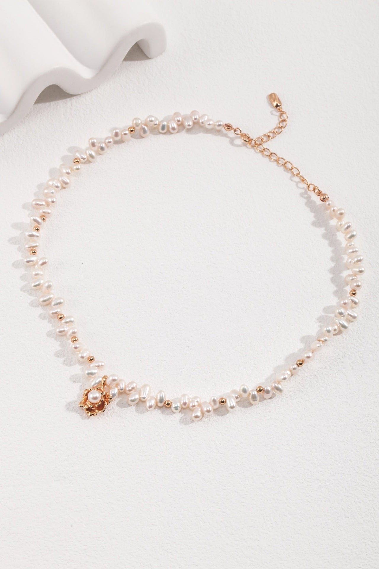 Discover the Elegant Vintage Gold Camellia Pearl Necklace with 925 Silver Pendant by Siren Mode, a delicate piece featuring irregularly shaped natural pearls interspersed with small gold beads. It boasts a gold clasp and an adjustable chain, with a gold flower charm and central pearl as its stunning focal point.