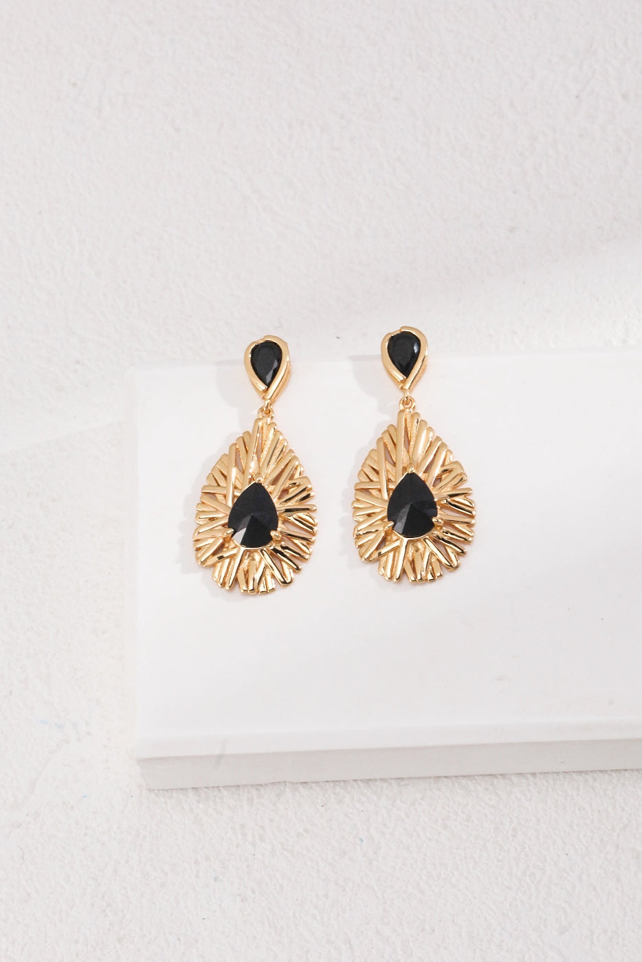 A pair of Siren Mode Vintage Gold 925 Silver Black Zircon Drop Earrings with teardrop-shaped black stones, displayed on a white surface. The exquisite black zircon earrings feature a sunburst design with intricate detailing around the stones.