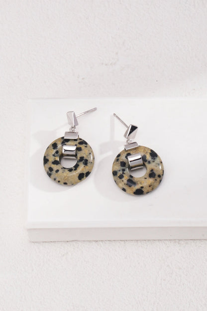 A pair of earrings from Siren Mode's collection, named "Vintage Gold 925 Silver Leopard Stone and Tiger's Eye Earrings," featuring circles of leopard stone with black spots on a beige background. Each earring includes a geometric 925 silver stud and a small rectangular silver link connecting to the stone. The earrings are displayed on a white surface.