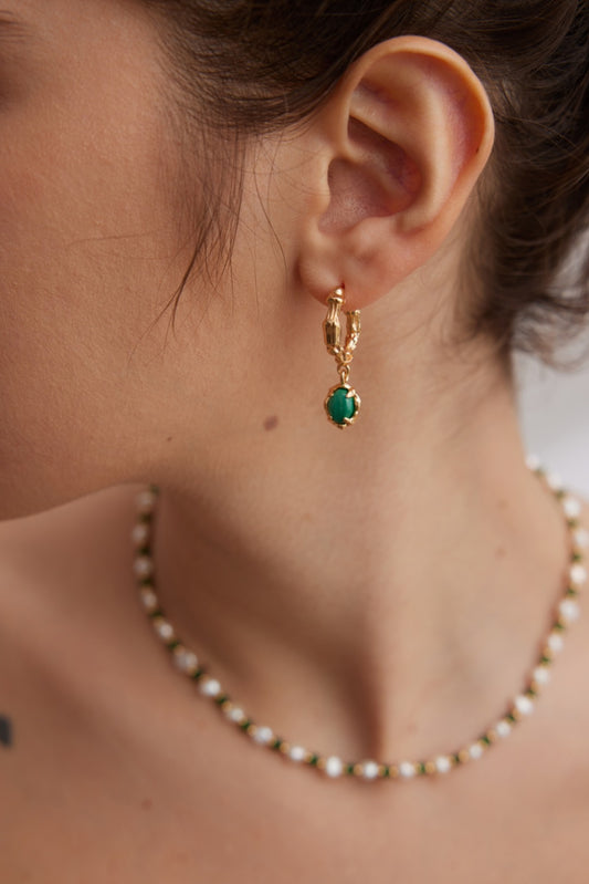 Close-up of a person wearing Siren Mode's Vintage Gold 925 Silver Malachite Hoop Earrings and a necklace with a daisy flower pattern. The image focuses on the ear and part of the neck and shoulder, showcasing the delicate jewelry and part of the person's hair tied up.