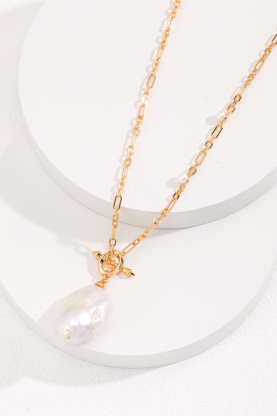 A vintage gold necklace from Siren Mode, featuring a 925 silver natural pearl and zircon pendant with a large, irregular-shaped natural pearl, is showcased on a minimalist white background. This elegant piece also includes a toggle clasp and a delicate, intricately designed chain, highlighting the sophistication of natural pearl jewelry.