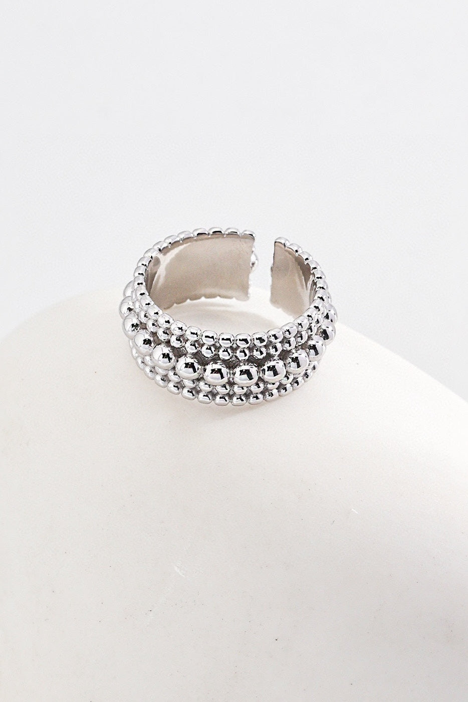 A close-up image of the Vintage Gold and White Gold 925 Silver Adjustable Beaded Ring by Siren Mode. The ring features a detailed beaded design with a gap at the top, indicating an adjustable fit. The beads are arranged in three rows, giving the ring a textured and intricate appearance akin to white gold beaded rings. The background is a smooth, light surface.