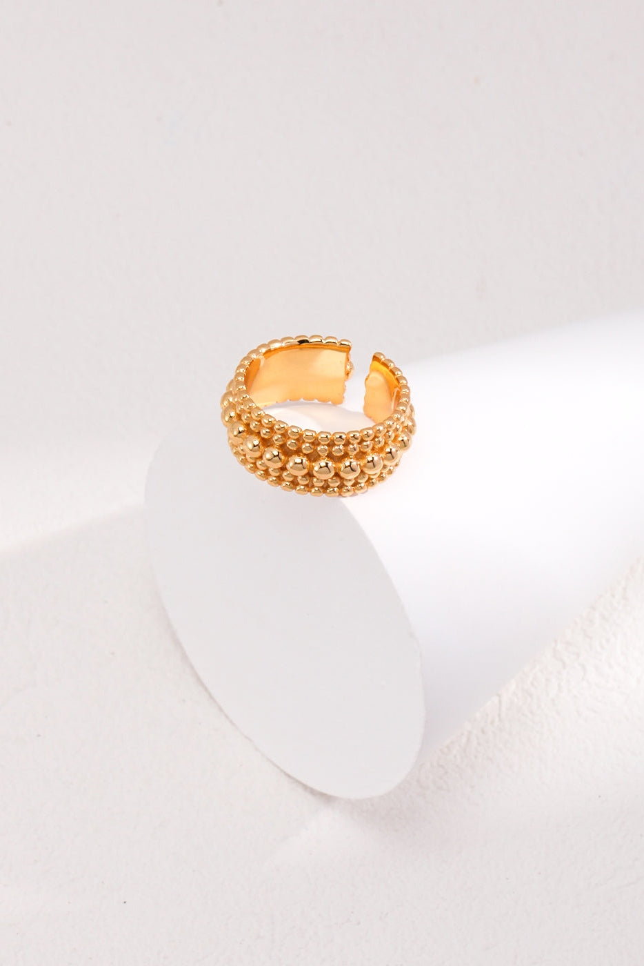 A Vintage Gold and White Gold 925 Silver Adjustable Beaded Ring by Siren Mode sits elegantly on a white, cylindrical display against a clean, light-colored background. The ring features a unique open-end style, enhancing its modern and sophisticated look.