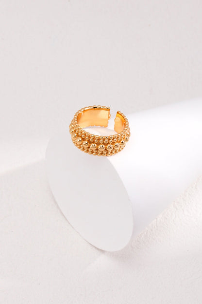 A Vintage Gold and White Gold 925 Silver Adjustable Beaded Ring by Siren Mode sits elegantly on a white, cylindrical display against a clean, light-colored background. The ring features a unique open-end style, enhancing its modern and sophisticated look.