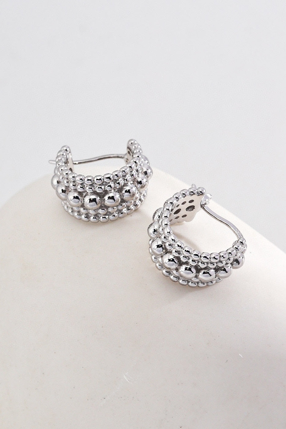 A pair of Vintage Gold and White Gold 925 Silver Beaded Hoop Earrings by Siren Mode, featuring a design with three rows of small, spherical beads. The earrings are displayed on a smooth, white, rounded surface against a light background.